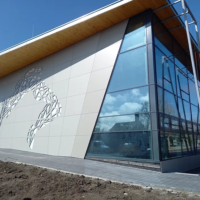 Sporthalle in Engen mit moderner Fassade, großer Glasfront und dekorativem Muster an der Wand, Fassadenarbeiten sichtbar