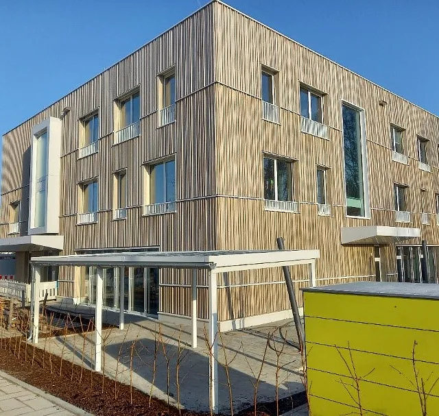 Neubau Kindergarten Jungerhalde Konstanz mit Holz-Beton-Skelettbauweise, Fassade aus vertikalen Holzlatten, drei Stockwerke, große Fenster, überdachte Eingänge