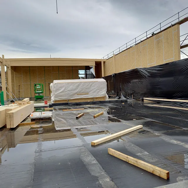Baustelle des Feuerwehrgerätehauses in Konstanz-Dettingen mit Holzrahmenkonstruktion und schwarzer Folie auf dem Boden bei bewölktem Himmel