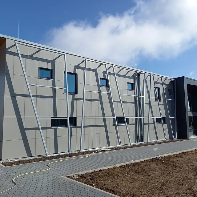 Fassade der Sporthalle in Engen mit grauen Paneelen und metallischen Fassadenrahmen unter blauem Himmel