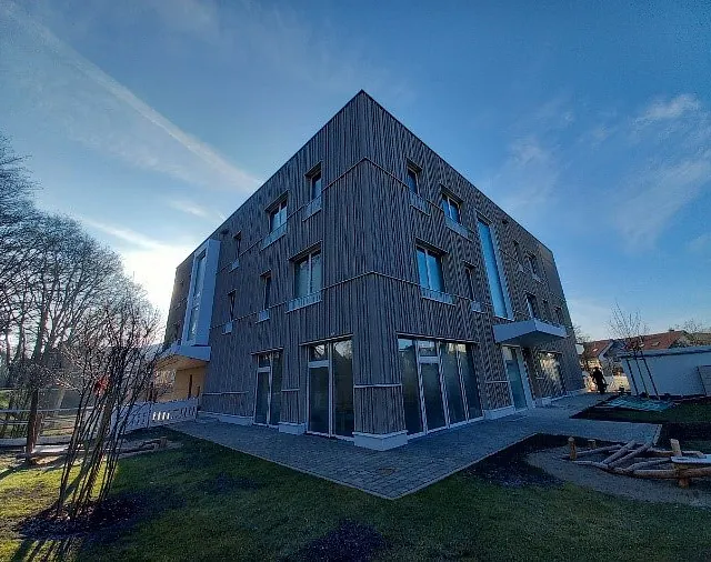 Neubau Kindergarten Jungerhalde Konstanz mit Außenwänden in Holz-Beton-Skelettbauweise, moderne Holzfassade bei klarem Himmel