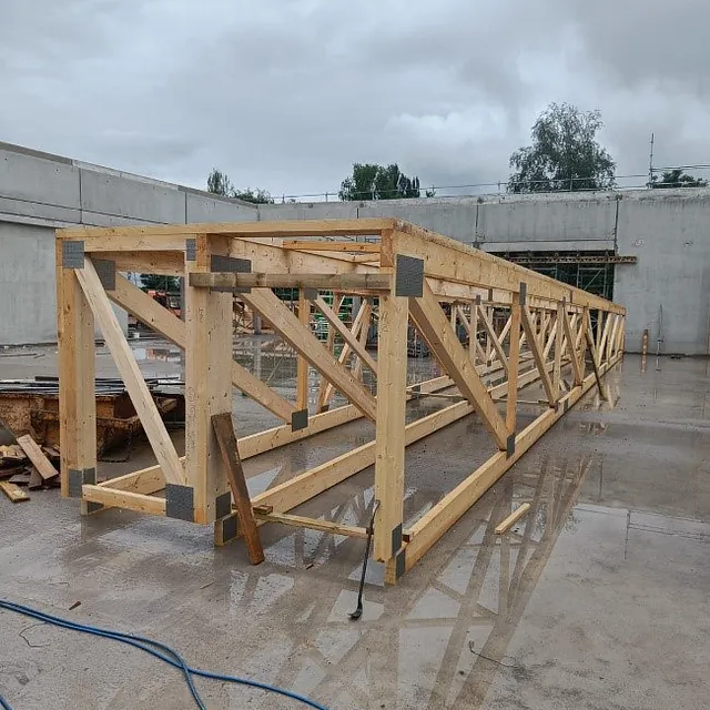 Holztragwerk für Dachkonstruktion auf nassem Betonboden beim Neubau von Aldi in Mühlhausen-Ehingen, Baustelle mit grauem Himmel