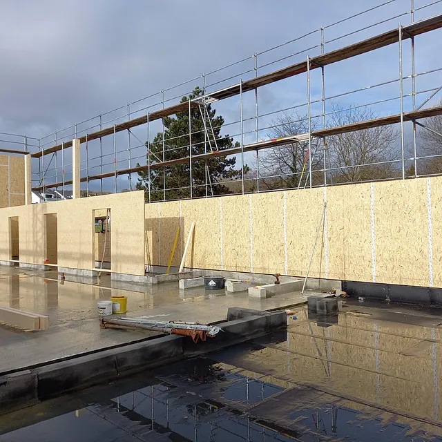 Baustelle des Feuerwehrgerätehauses in Konstanz-Dettingen mit aufgestellten Holzplattenwänden und Gerüst im Hintergrund